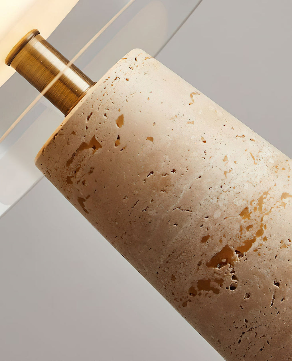 Close view of the brass stem joining the travertine base on this Clérachic lamp, with the pitted stone surface in sharp focus.