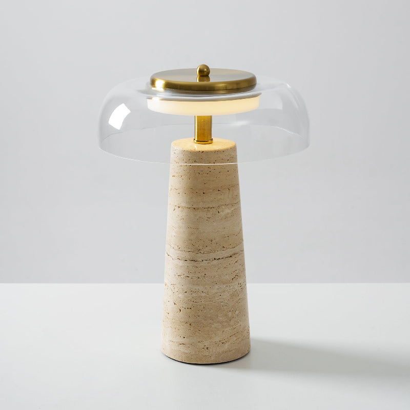 The brass stem and a glowing ring beneath a clear glass dome on this Clérachic table lamp, with a banded travertine base.