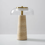 Clérachic table lamp with a clear glass dome set slightly off-centre over a brass stem and a pale banded travertine base.