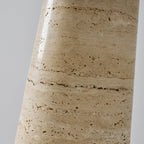 Close view of the banded, pitted travertine on the base of this Clérachic table lamp, with fine dark veining running across it.