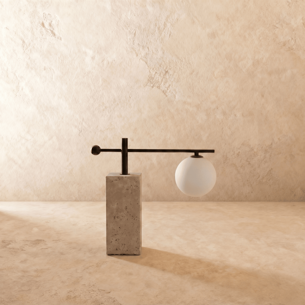 A Clérachic table lamp's frosted glass globe hangs from a black metal arm over a travertine-style base.