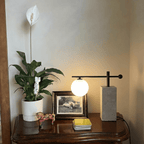 A Clérachic table lamp glows beside a framed photo and a peace lily on a dark wood dresser.