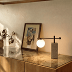 A Clérachic table lamp glows on a marble-topped console beside a framed abstract painting.