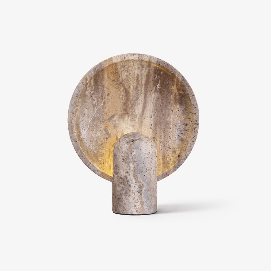 Travertine disc table lamp from Clérachic on a plain white backdrop, with a warm glow lighting the inside of the round stone dish.