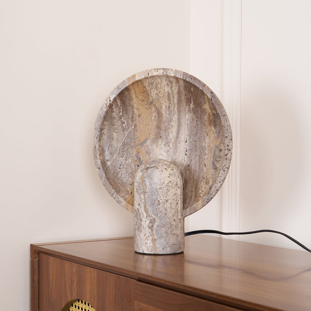 Angled view of this Clérachic lamp on a wooden cabinet, the veined disc leaning above a smooth rounded stem.