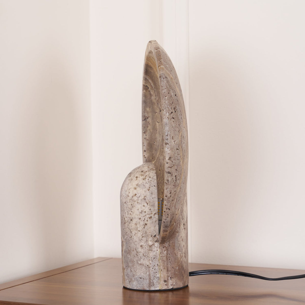 Side profile of this Clérachic lamp, the thin stone disc curving up behind the rounded travertine stem.