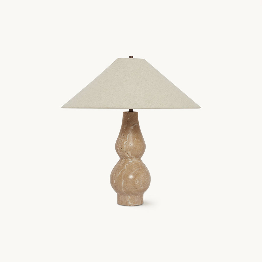 On a plain white backdrop, this Clérachic table lamp has a wide beige linen shade over a double-curved travertine base.