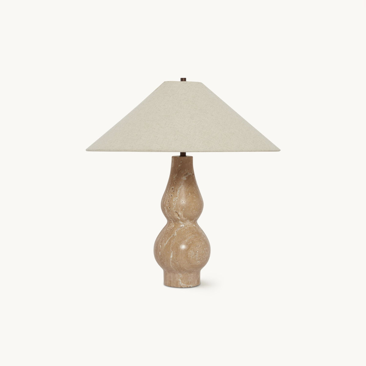 On a plain white backdrop, this Clérachic table lamp has a wide beige linen shade over a double-curved travertine base.