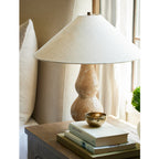 Close on a bedside table beside a linen headboard, this Clérachic table lamp stands above a stack of books and a small brass bowl.