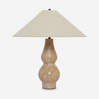 Studio view of this Clérachic table lamp on a light grey backdrop, its broad linen shade over a veined travertine base in warm sand.