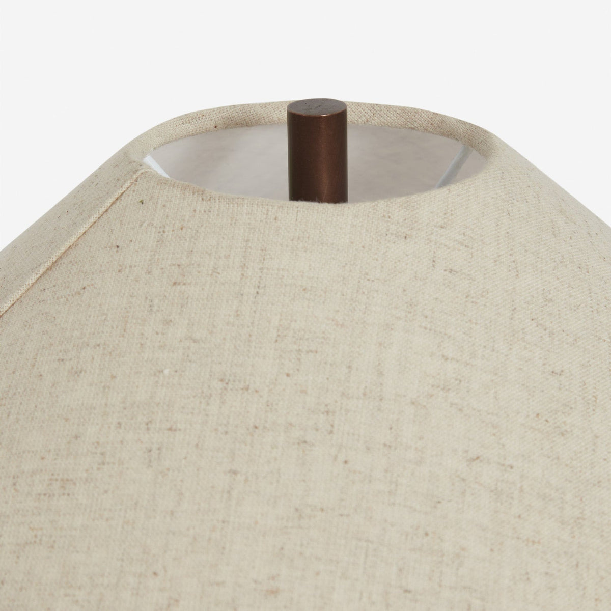 Looking up into the top of this Clérachic table lamp's linen shade, a dark metal finial and the woven texture of the fabric in view.