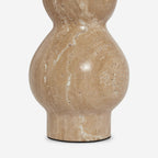 Close view of the rounded travertine base of this Clérachic table lamp, its veining and small natural pits clear.
