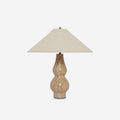 Clérachic table lamp on a light grey backdrop, a beige linen shade above a sand-coloured travertine base with dark metal detail at the foot.
