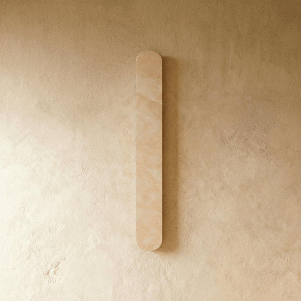 Clérachic slim cream travertine wall light with rounded ends, switched off and mounted on a warm limewashed wall.