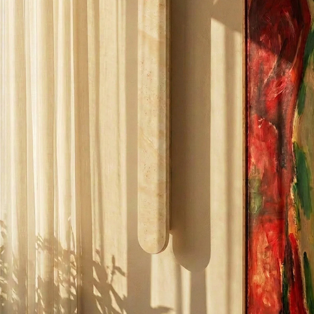 Clérachic cream travertine wall light close up, with its rounded end and stone grain catching sunlight beside a sheer curtain.