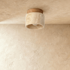 Clérachic short travertine ceiling light with a pale wood canopy, switched off to show the pitted stone and bare bulb inside.