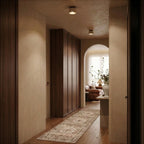 Clérachic short travertine ceiling lights glowing along a warm hallway with a walnut wardrobe, an arched opening and a runner.