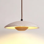 The wide travertine shade of this Clérachic pendant glows warm from beneath, with a light wood bowl at the centre.