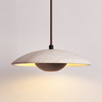 Clérachic pendant with a veined stone shade and a dark walnut-toned bowl, casting warm light onto a pale wall.