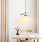 Clérachic travertine pendant glowing above a pale wood café table, with slatted wood panelling on the left.