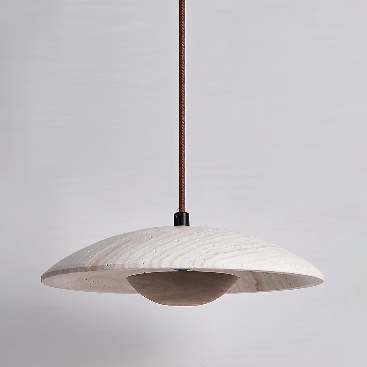 Clérachic pendant in veined travertine with a dark walnut-toned bowl beneath, shown unlit on a grey backdrop.