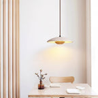 Clérachic travertine pendant hangs above a pale wood table with a sprig in a vase, beside slatted wood panelling.