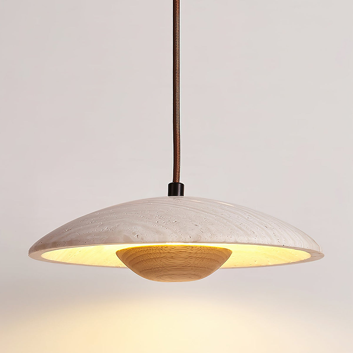 A Clérachic pendant with a banded travertine shade and a light wood bowl, shot close with a warm glow below.