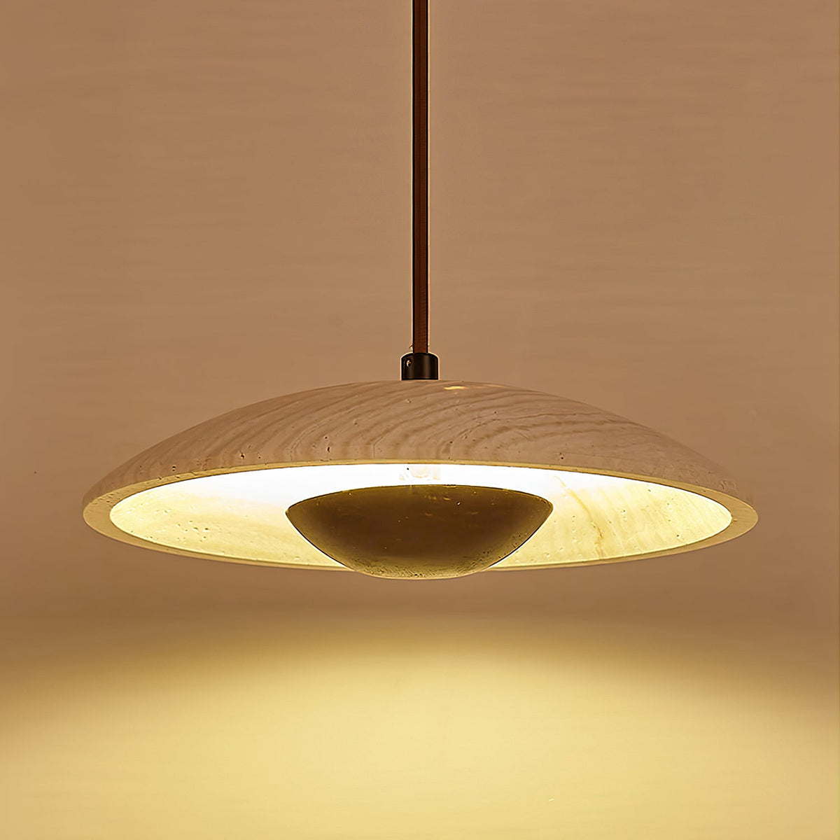 Underside view of a Clérachic pendant, with a rim of warm light around the stone shade and a dark bowl in the middle.