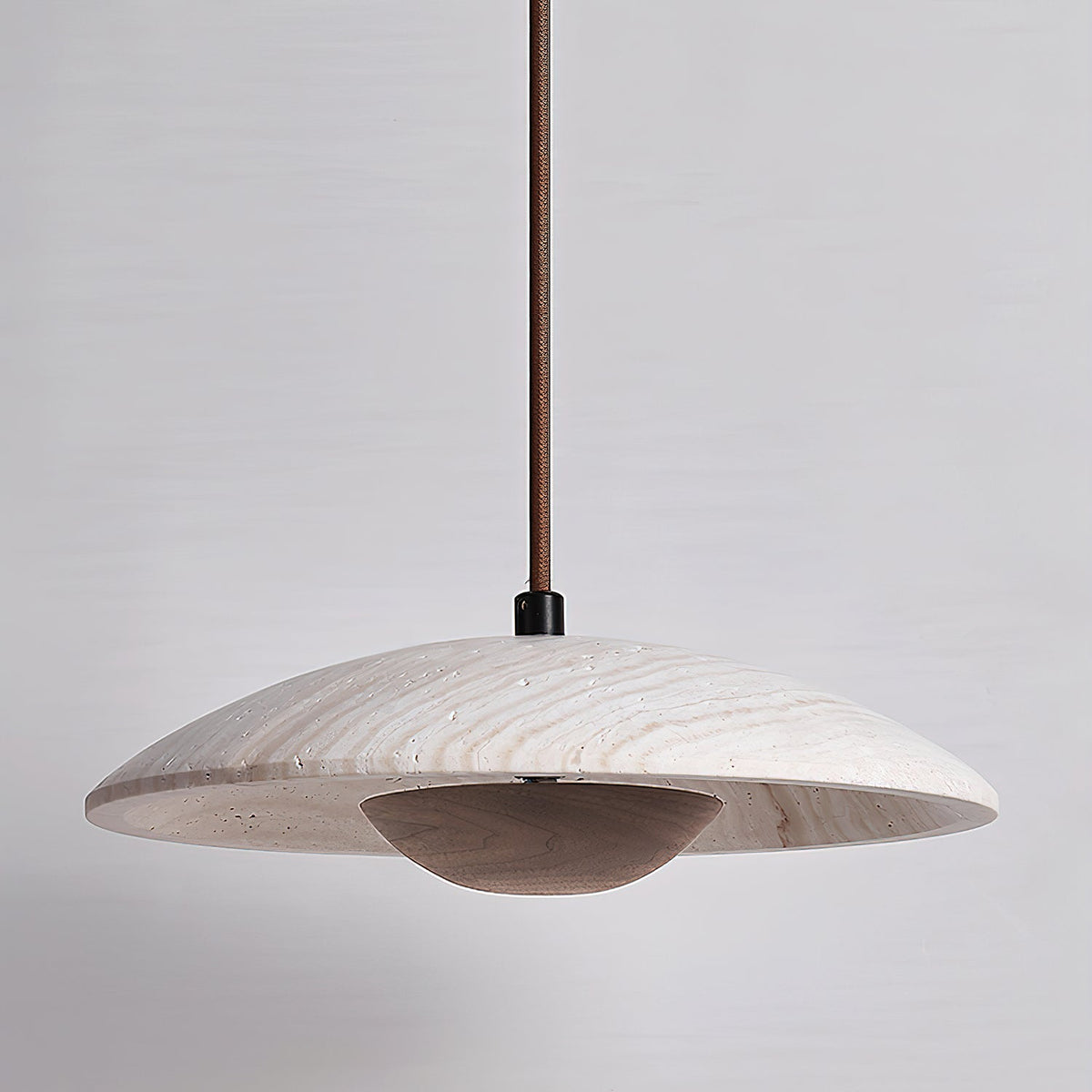 Clérachic pendant with a travertine shade and a dark walnut-toned bowl, shown unlit against a soft grey wall.