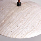 Close view of the veined surface and fabric cord entry at the top of this Clérachic pendant's travertine shade.