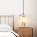A Clérachic travertine pendant hangs in a bedroom, lighting a slatted headboard and a bedside chest.