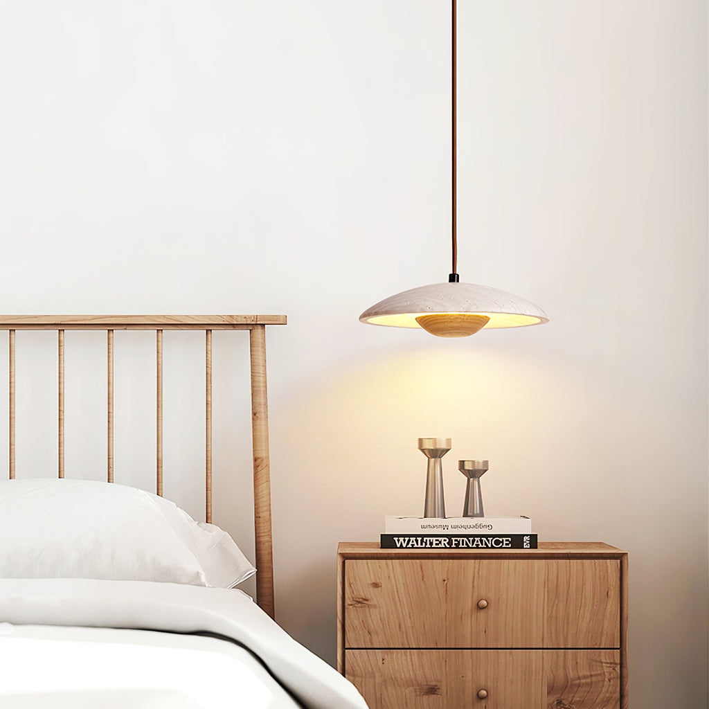 Above a slatted headboard and a wooden bedside chest, the stone shade of this Clérachic pendant glows warm.