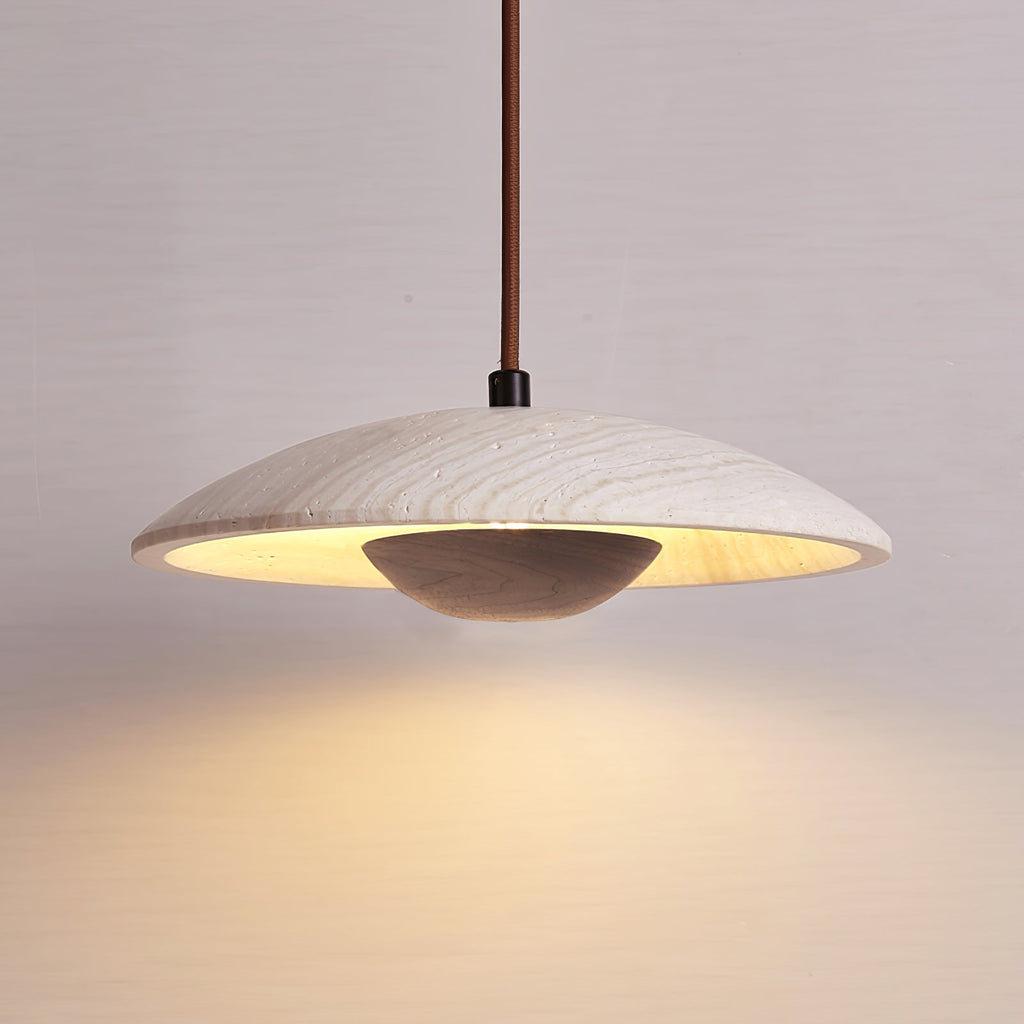 A Clérachic pendant with a dark walnut-toned bowl under a travertine shade hangs against a soft mauve-grey wall.