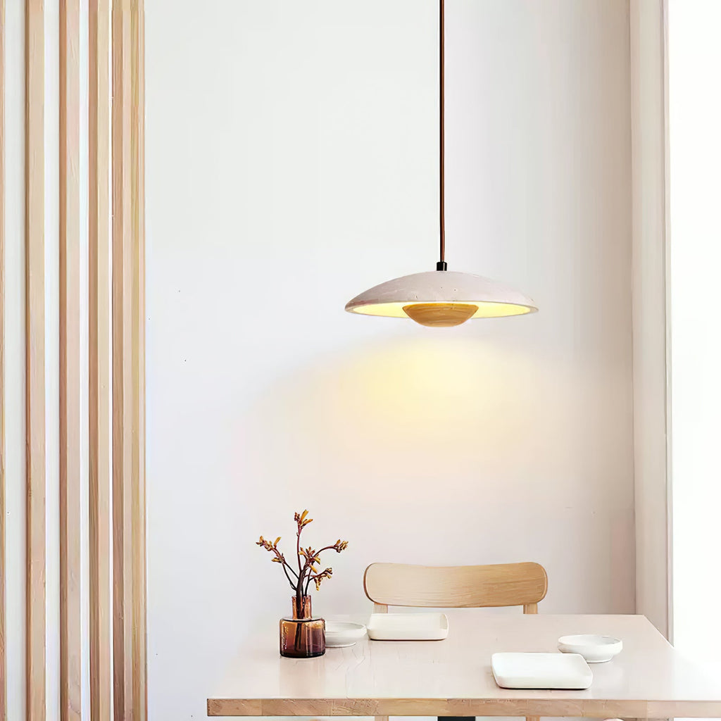A Clérachic travertine pendant lights a pale wood table and café chair, with slim vertical wood slats beside it.