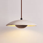 This Clérachic pendant with a dark walnut-toned bowl glows warm from beneath its wide travertine shade.