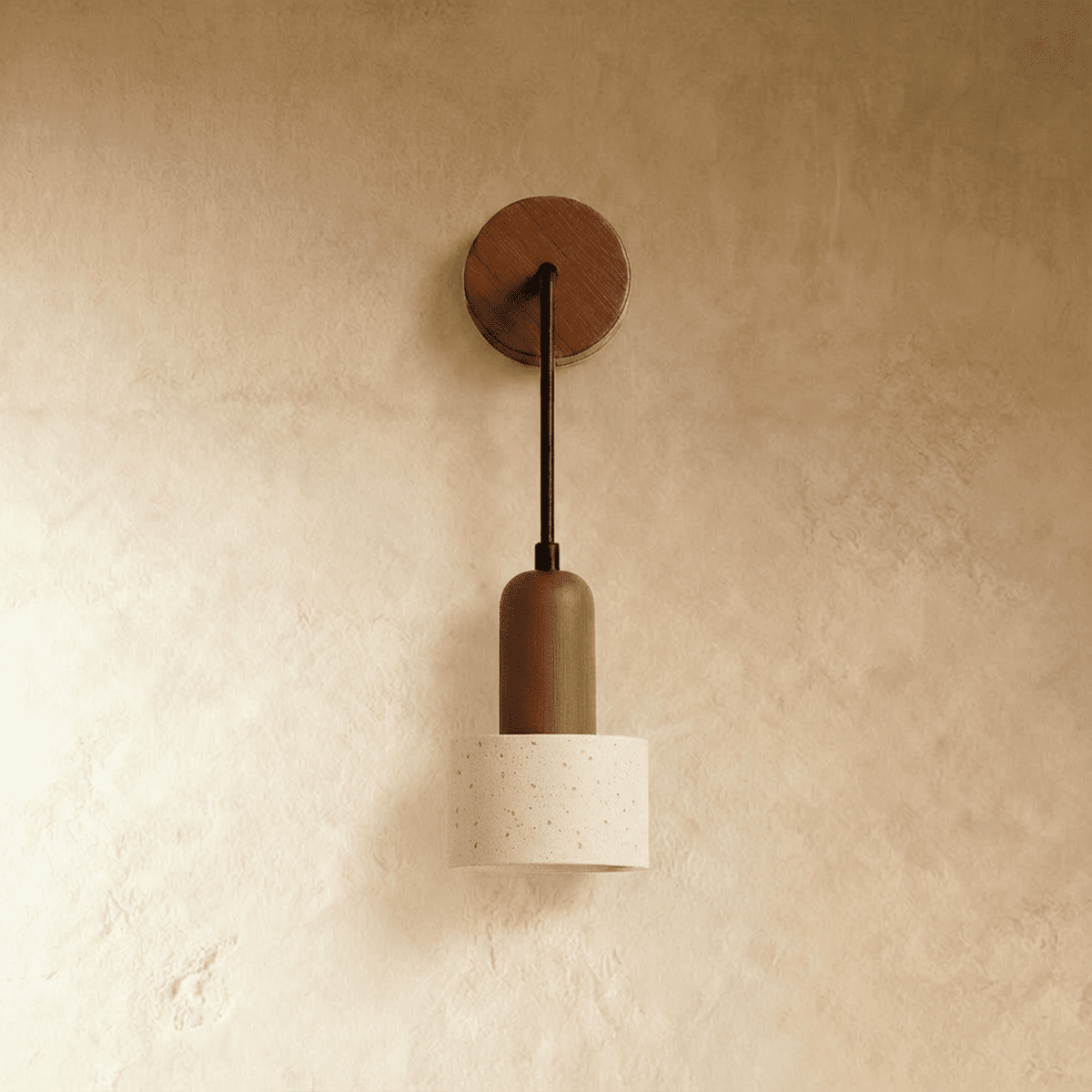 Clérachic wall lamp with a wood backplate, bronze-toned stem and a cylindrical travertine shade on a warm plaster wall.