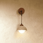 Clérachic wall lamp with a travertine dome shade over a frosted globe bulb, hung from a wooden backplate and thin arm.