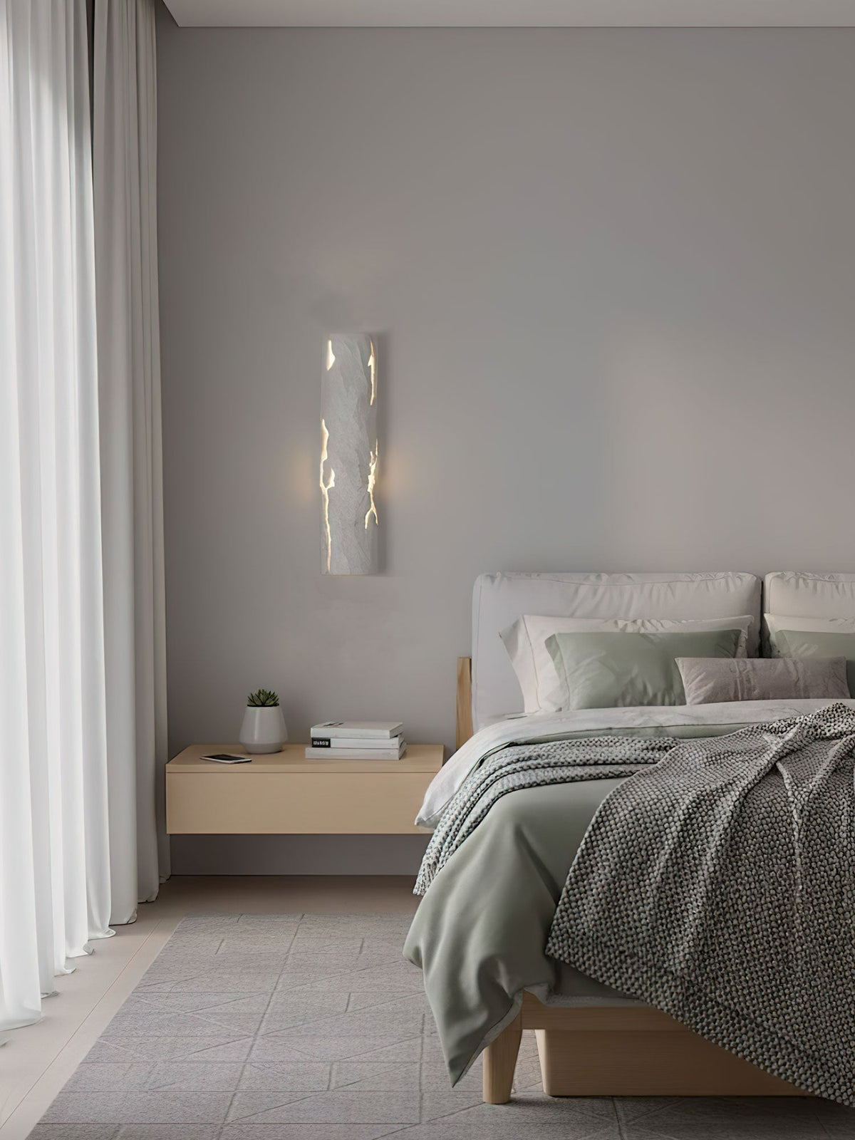 Seen across a calm bedroom, a white Clérachic wall light glows through its fine cracks above a pale wood bedside table.