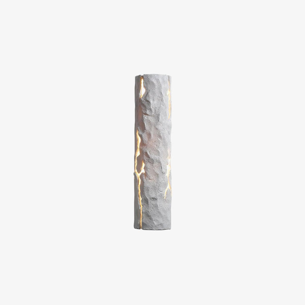 A slim white Clérachic wall light with a rough, faceted surface and bright cracks, shown on a plain light-grey backdrop.