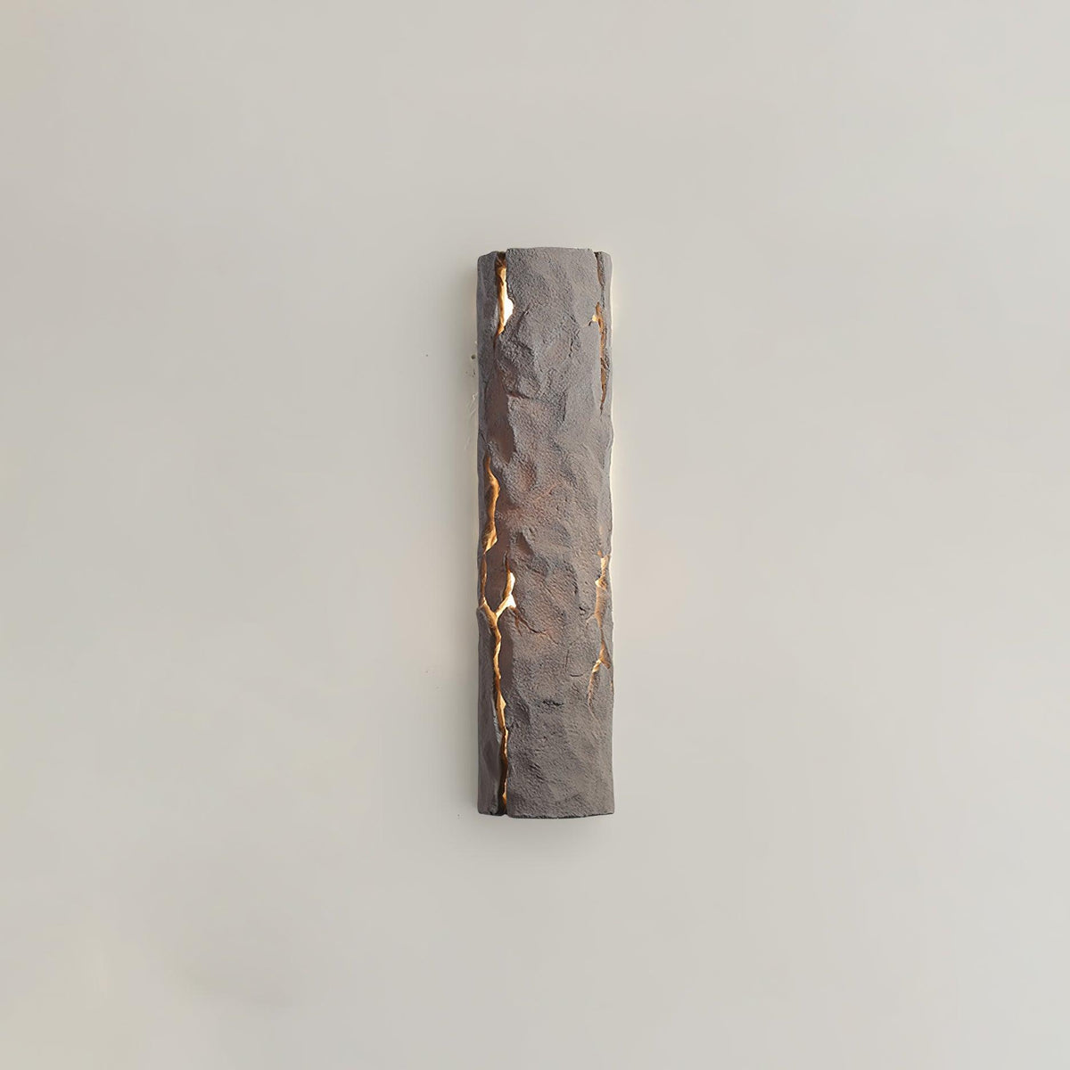 A taupe-toned version of this Clérachic wall light, its chiselled surface lit through cracks, on a warm greige wall.
