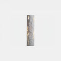 A white Clérachic wall light with a chiselled, cracked surface and light shining through the fissures, on a pale backdrop.