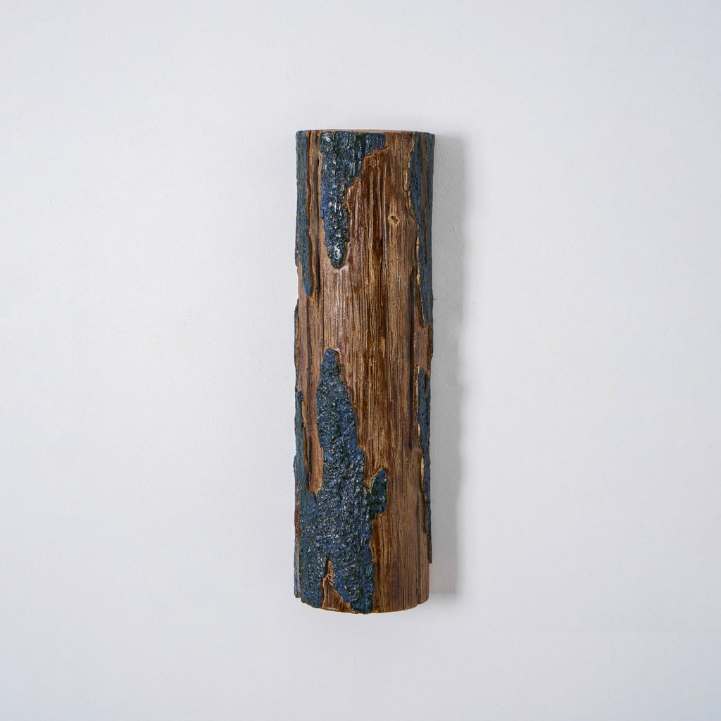 Front view of a Clérachic Bark wall light, with raw wood grain in the centre and blue-grey bark texture down both sides.