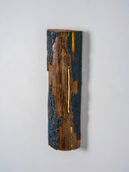 A Clérachic Bark wall light seen slightly from the side, with a golden light line glowing down the middle of the wood.