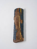 Angled view of a Clérachic Bark wall light, with a bright slit running down its length and a cut end showing at the bottom.