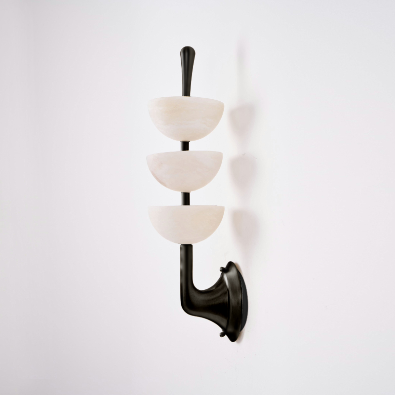 The matte black finish of the Clérachic triple-dome wall sconce, three pale alabaster bowls stacked on a dark rod and bracket.
