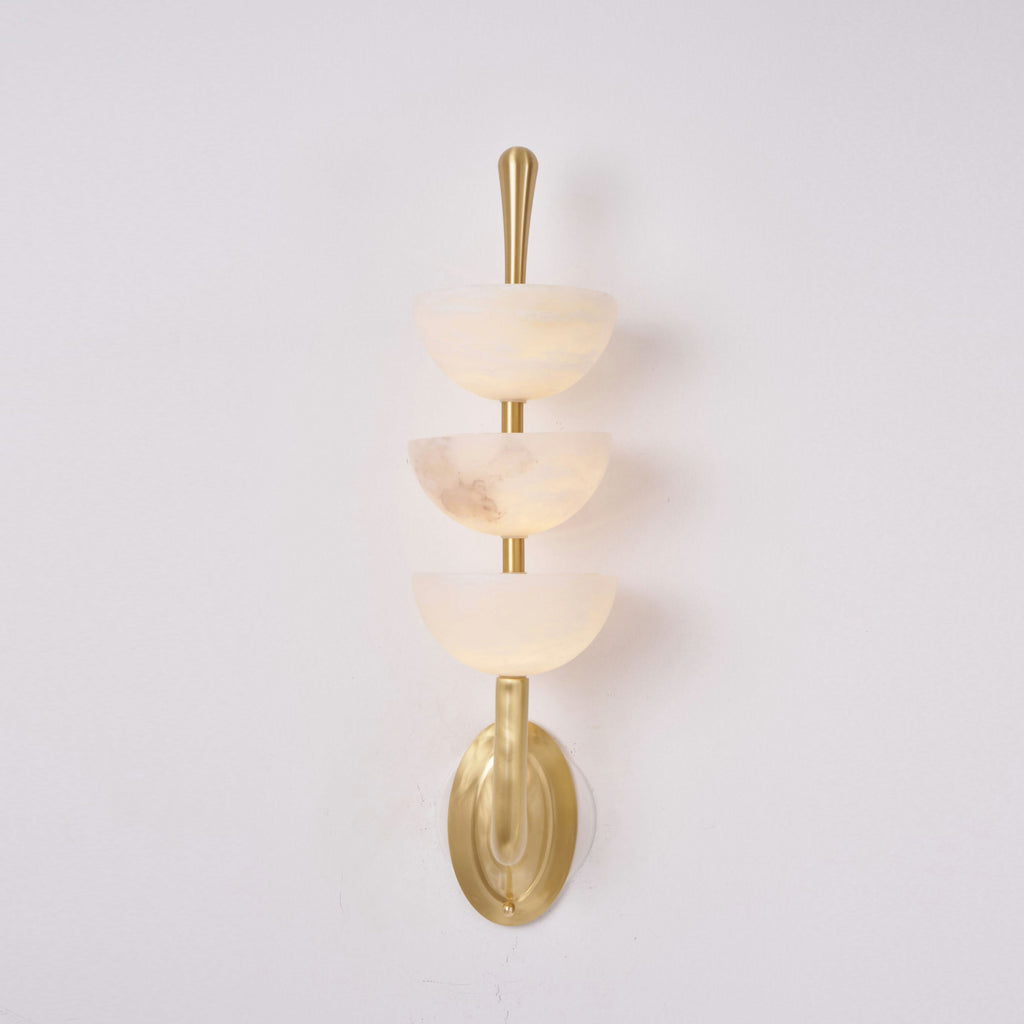 Clérachic alabaster wall sconce head-on, one bowl carrying a darker rust-grey vein of its own against the warm off-white stone.