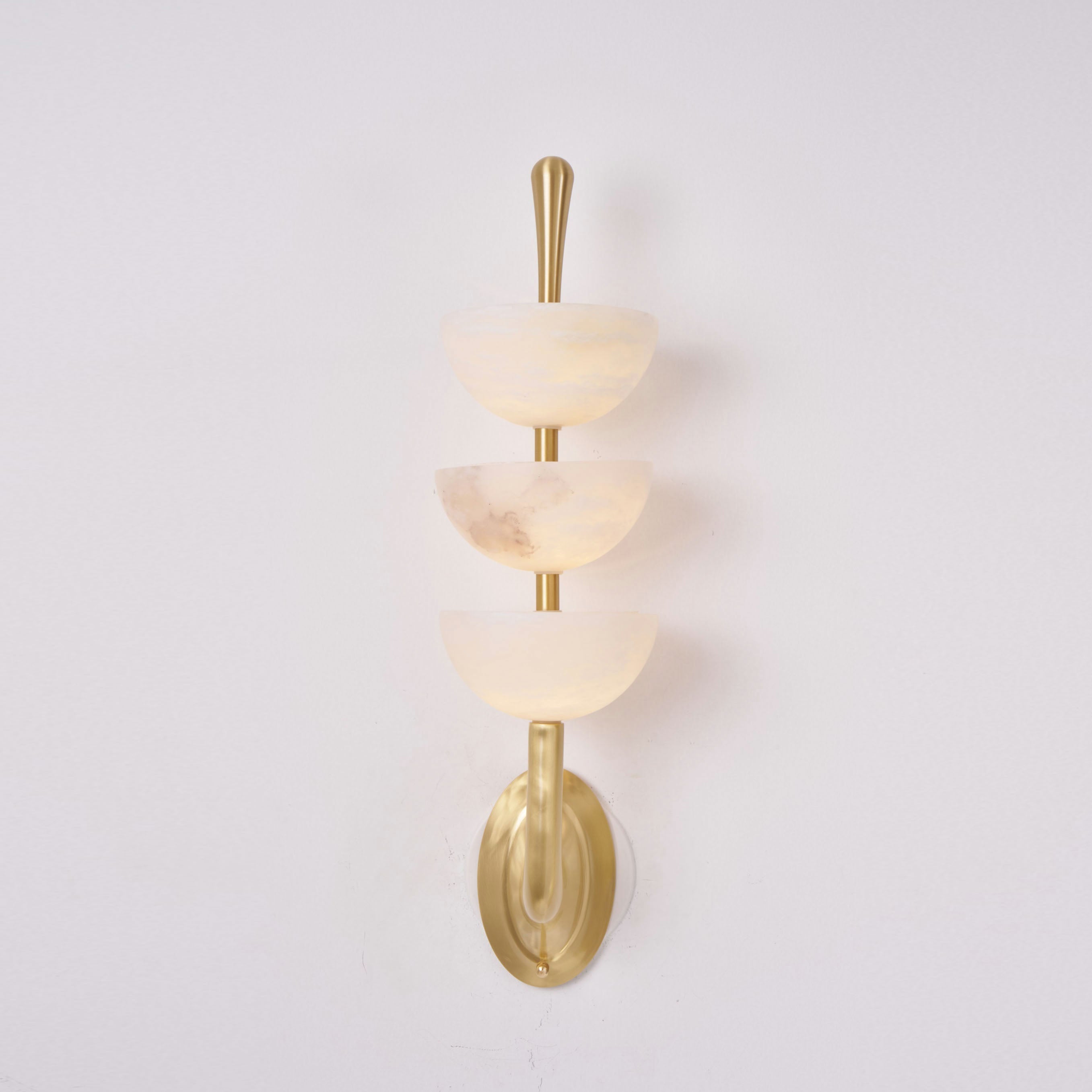 Clérachic alabaster wall sconce head-on, one bowl carrying a darker rust-grey vein of its own against the warm off-white stone.