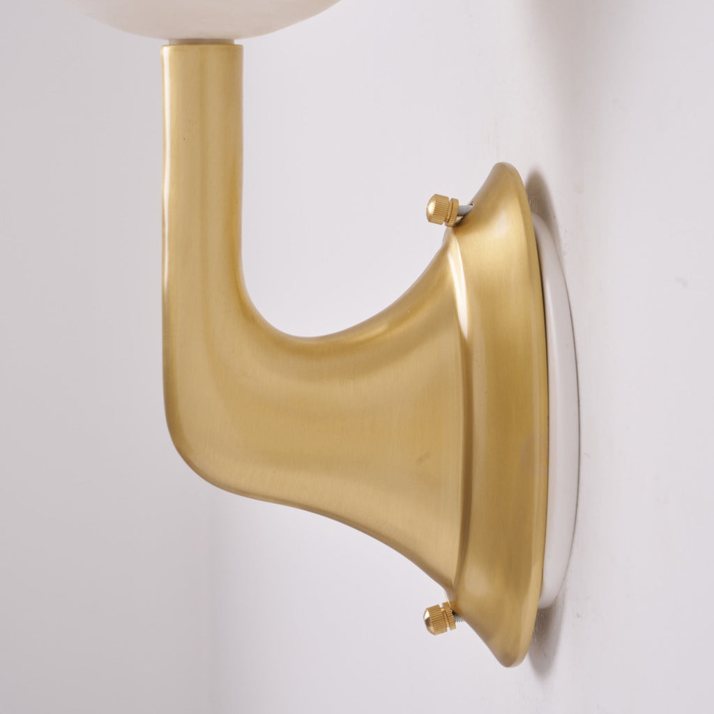 Detail of the Clérachic sconce's brass wall bracket and oval backplate, held by two small knurled screws top and bottom.