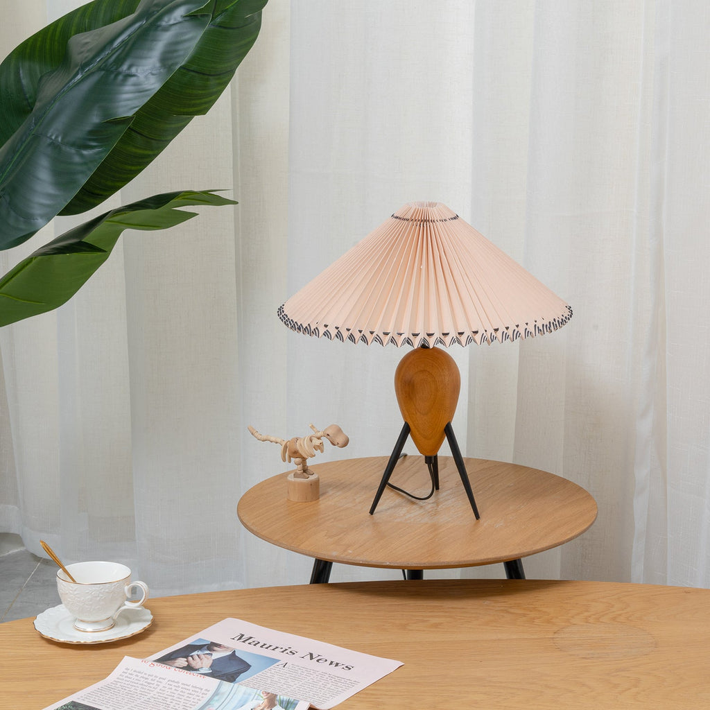 Unlit Clérachic table lamp on a round wooden table, with a cup and saucer and a leafy plant in the foreground.