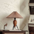 On a dark wood console against textured plaster, this Clérachic table lamp stands near magazines and a small candle.